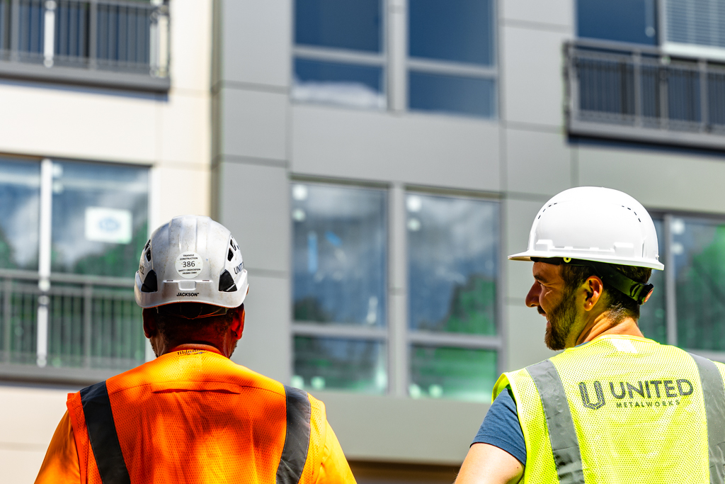 Two Build United crew members looking up at a nearly finished façade