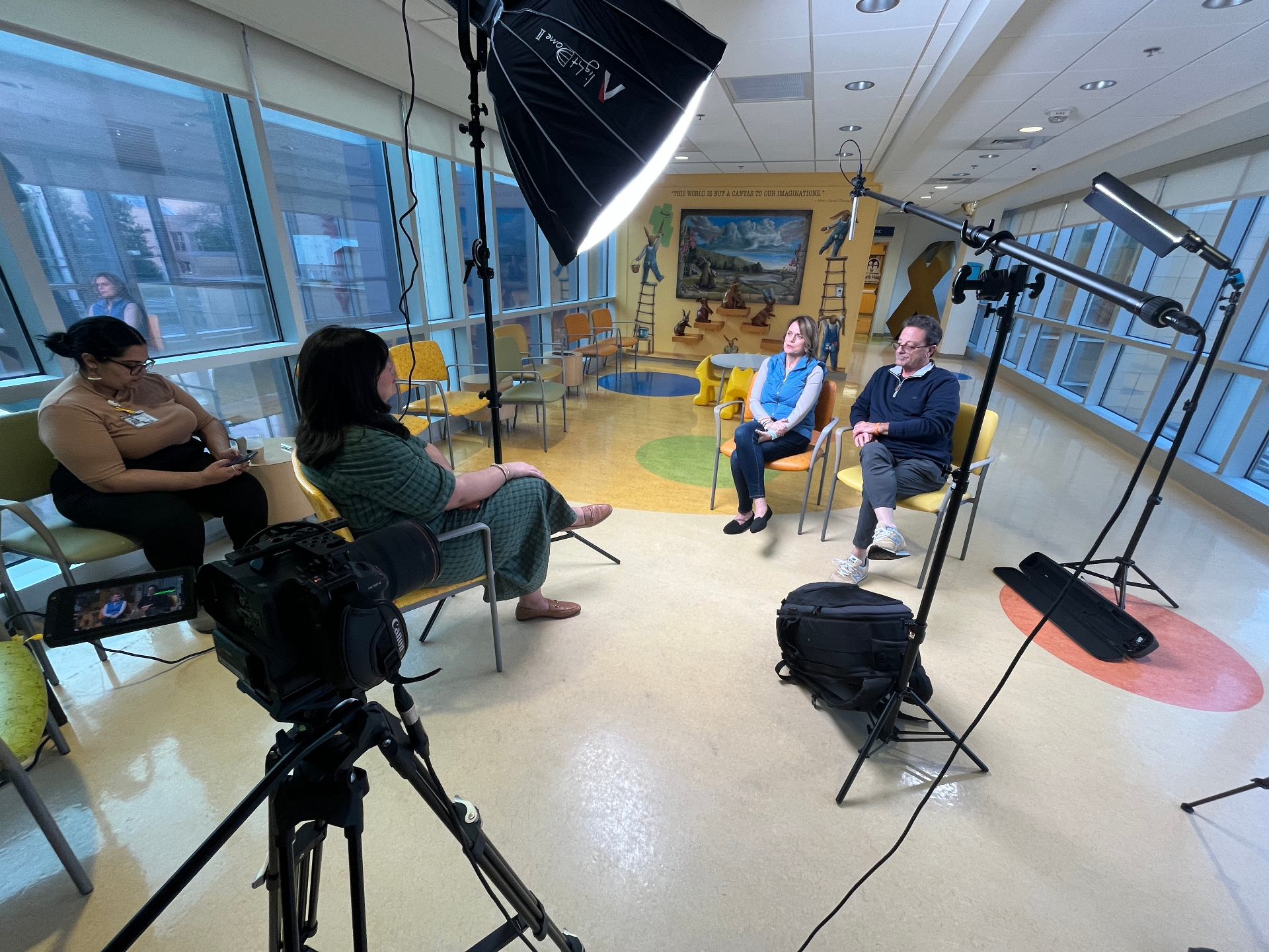 A small crew setting up an interview in a hospital waiting room