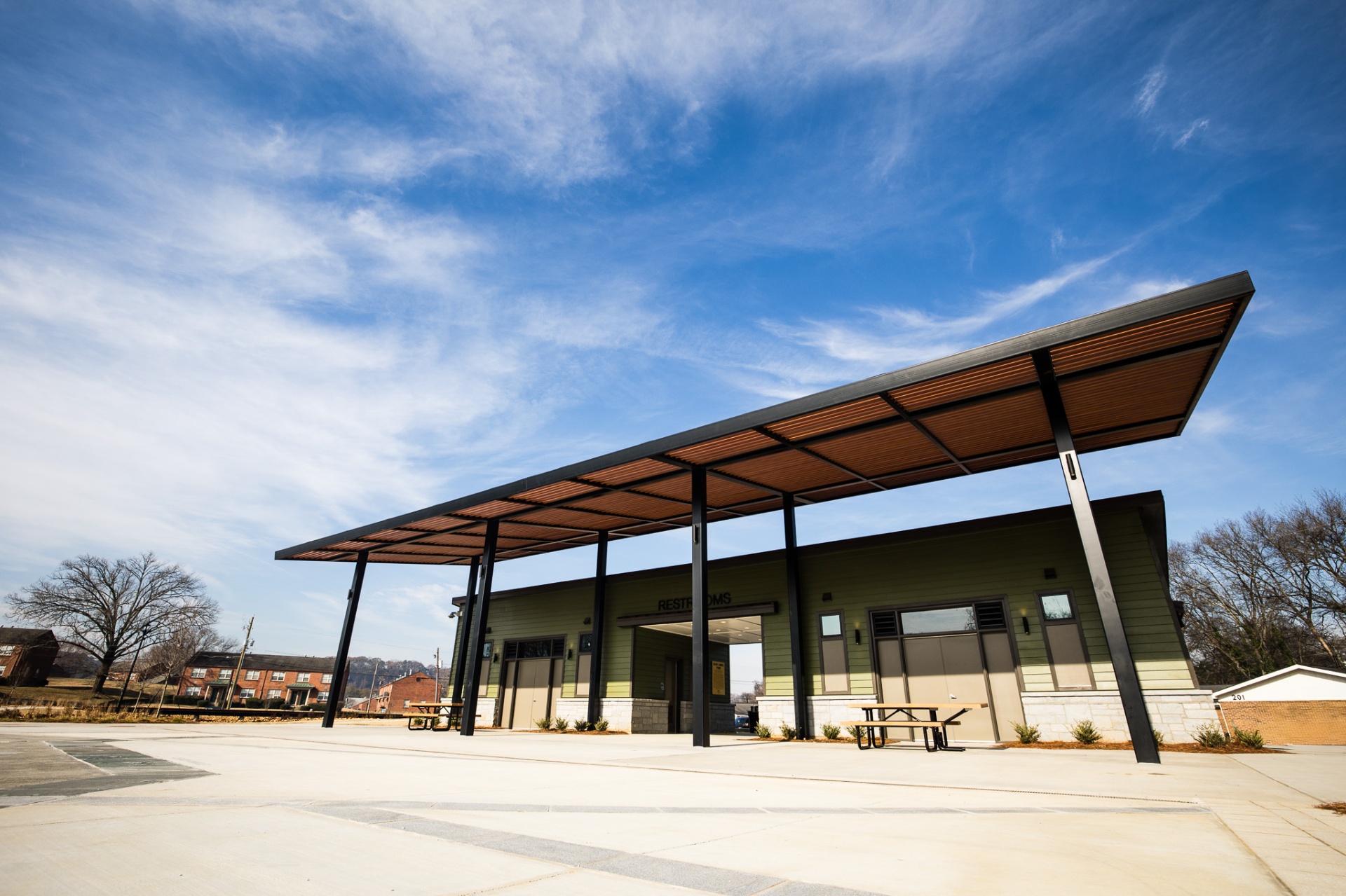 A long cedar-and-steel pavilion under a wide winter sky